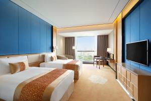 a hotel room with two beds and a flat screen tv at Ramada Foshan Nanhai in Nanhai