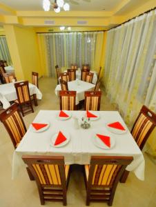 un comedor con mesas blancas y sillas con servilletas rojas en Camves Inn en Sighetu Marmaţiei