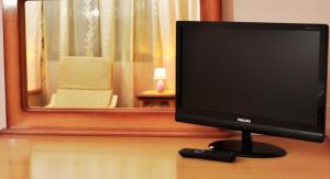 a computer monitor on a table with a remote control at Camves Inn in Sighetu Marmaţiei