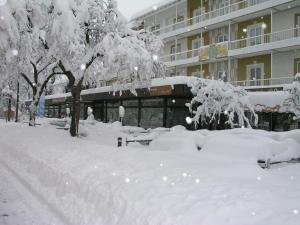 
a snow covered park bench in front of a building at Kurhotel Luitpold in Bad Wörishofen
