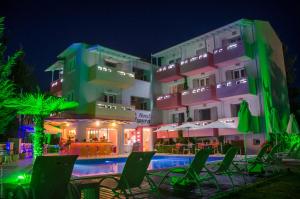 um hotel com cadeiras e uma piscina à noite em Palmyra Hotel em Nydri