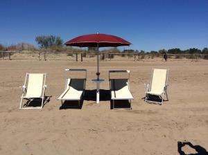 a group of chairs and an umbrella on the beach at Locanda da Scarpa in Cavallino-Treporti