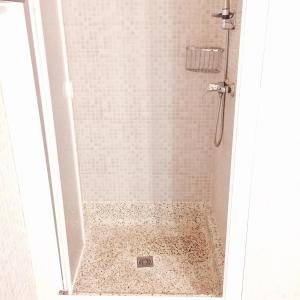 y baño con ducha y suelo de baldosa. en Apartament Carme, en Llançà