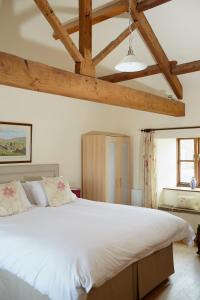 um quarto com uma grande cama branca com vigas de madeira em Dallow Hall Barns em Grantley