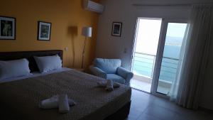 1 dormitorio con 1 cama, 1 silla y 1 ventana en Aegean View Villa, en Loutraki