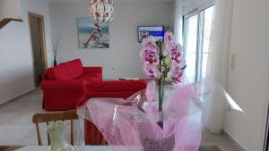 sala de estar con sofá rojo y mesa con flores rosas en Aegean View Villa, en Loutraki