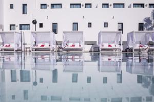 4 sillas sentadas en el agua frente a un edificio en Migjorn Ibiza Suites & Spa, en Playa d'en Bossa