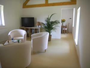 sala de estar con sillas blancas y TV en Verreveld, en Londerzeel