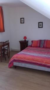 a bedroom with a bed and a table with a lamp at Chez Ghislaine in Verdun-sur-Meuse