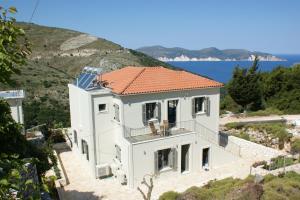 a white house with an orange roof on a hill at Myrtos View Apartments in Anomeriá