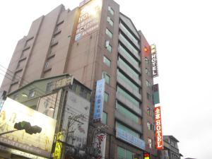 a tall building with many signs in a city at Family Hotel Taipei in Zhonghe