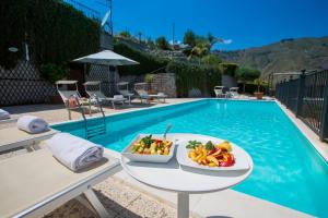 a table with bowls of fruit on it next to a swimming pool at Casale Di Caterina in Taormina