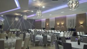 a banquet hall with white tables and chairs and chandeliers at Gros Hotel - Leskovac in Leskovac