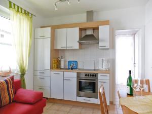 een keuken met witte kasten en een rode bank in een kamer bij Ferienwohnung Amann in Nonnenhorn