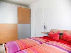 een slaapkamer met een bed met rode en paarse kussens bij Ferienwohnung Amann in Nonnenhorn