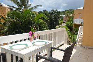 a white table and chairs on a balcony with palm trees at Pelican Pearl in Simpson Bay