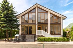 una casa con grandes ventanas y un árbol en Saulės Namai, en Palanga