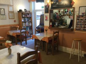 un restaurante con mesas y sillas y un estante de libros en The Hotel Wilmar en Blackpool