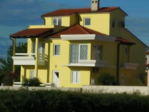 une maison jaune avec un toit rouge dans l'établissement Villa Kamelija, à Fažana