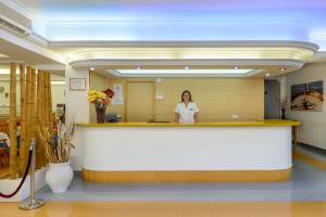 Una donna in piedi dietro un bancone in un atrio dell'ospedale di Hotel Vibra Vila a Ibiza Città