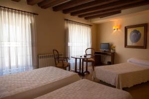 a bedroom with two beds and a table and a television at Tirso de Molina in Almazán