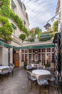 eine Terrasse mit Tischen und Stühlen vor einem Gebäude in der Unterkunft Hôtel Duc De St-Simon in Paris