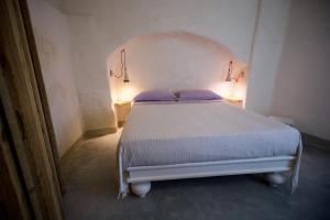 a white bed in a room with two purple pillows at Villa Mimi' in Nardò