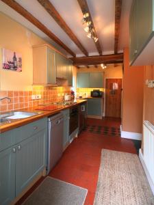 a kitchen with blue cabinets and a red tile floor at Bryn Ffynnon Holiday Cottage Llanrwst in Llanrwst
