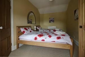 een slaapkamer met een bed met rode bloemen erop bij Bryn Ffynnon Holiday Cottage Llanrwst in Llanrwst