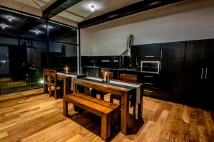 cocina con mesas y sillas de madera y ventanas grandes en The Bungalow, en Nuwara Eliya