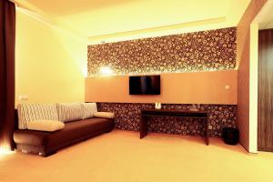a living room with a couch and a tv on a wall at Ipari Park Panzió in Szolnok +13 photos