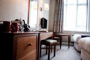 una camera d'albergo con scrivania e specchio di The Mad Hatter Hotel a Londra