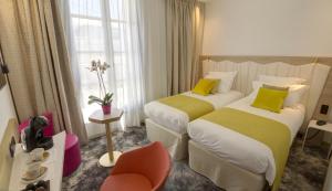 um quarto de hotel com duas camas e uma cadeira em Best Western Plus Comedie Saint Roch em Montpellier