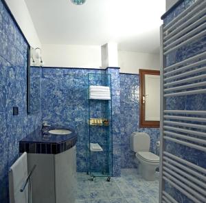 a blue tiled bathroom with a sink and a toilet at Donatello Penthouse in Florence