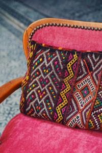 un bolso colorido sentado en la parte superior de una silla rosa en Riad Anata, en Fez