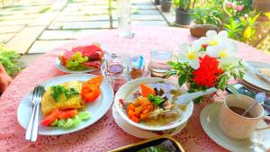 una mesa rosa con platos de comida y flores. en Loy Manee House en Phra Nakhon Si Ayutthaya