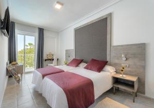 1 Schlafzimmer mit 2 Betten und einem großen Fenster in der Unterkunft Hotel Vibra Marco Polo II - Adults only in Sant Antoni de Portmany