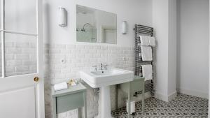 a white bathroom with a sink and a mirror at Le Clos Saluces in Avignon