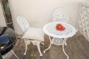 zwei weiße Stühle und ein Tisch mit Blumen drauf. in der Unterkunft De Kothuize 4 in Graaff-Reinet + 1 Foto
