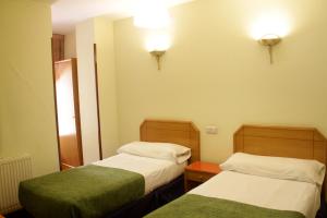 a hotel room with two beds and two lamps at Hostal Arlanzón in Burgos
