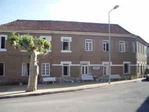 a large brick building with benches in front of it at Pensao Lourenco in Curia