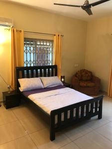 a bedroom with a bed and a chair and a window at Royal German Apartments in Accra