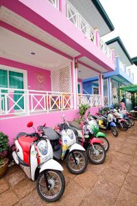 een rij motorfietsen geparkeerd voor een roze gebouw bij HappyLove1 in Ko Larn
