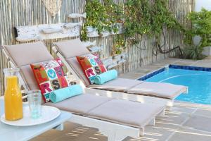 una silla con almohadas junto a la piscina en Shore's Edge Luxury Oceanfront Home, en Hermanus