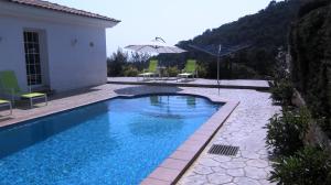 una piscina con sombrilla junto a una casa en Can Ronia, en Tossa de Mar