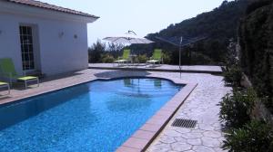 a swimming pool with an umbrella next to a house at Can Ronia in Tossa de Mar