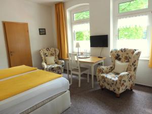 Schlafzimmer mit einem Bett, einem Schreibtisch und Stühlen in der Unterkunft Gästehaus Kehne in Horn-Bad Meinberg