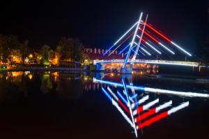 un puente con luces en el agua por la noche en Avanti Resort Mikołajki , w centrum przy jeziorze i promenadzie, śniadanie i obiad lub obiadokolacja w cenie en Mikołajki
