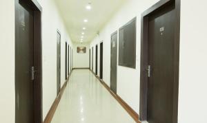 einen Flur mit schwarzen Türen, weißen Wänden und weißen Böden in der Unterkunft Treebo Trend Dee Intercontinental Amritsar in Amritsar