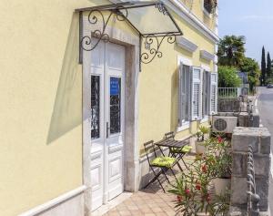 a yellow building with a white door and a bench at Apartments Hortensia in Opatija